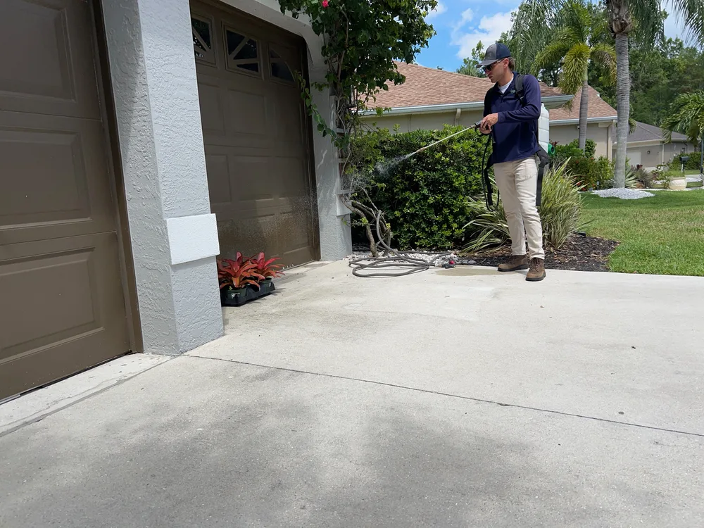 Professional pest control technician spraying treatment around home exterior and landscaping in Florida