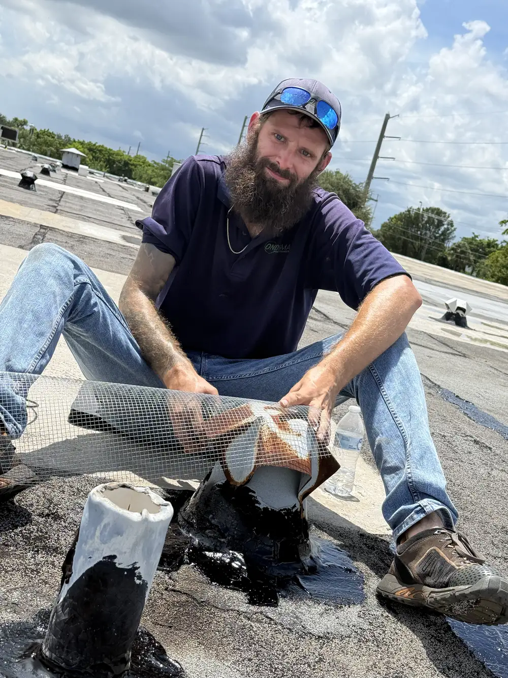 On Demand worker applying mesh and sealant around a roof pipe penetration on a commercial flat roof