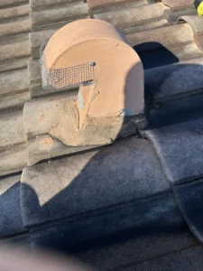 Terracotta roof vent with wire mesh screen and mortar repair for rodent exclusion on tile roof