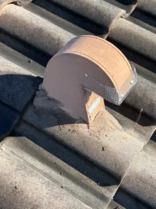 Terracotta roof vent fitted with wire mesh screen for rodent exclusion on tile roof