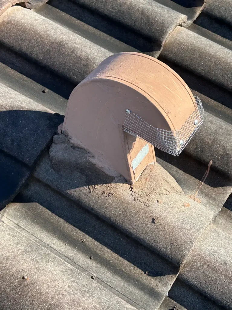 Terracotta roof vent fitted with wire mesh screen for rodent exclusion on tile roof