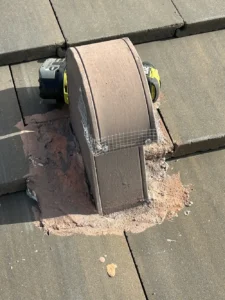 Curved roof tile vent sealed with wire mesh and mortar bedding for rodent exclusion