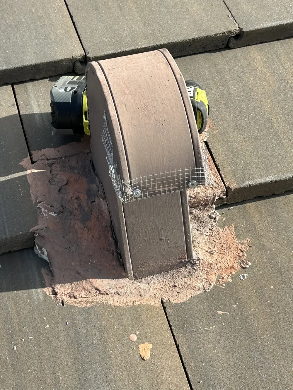 Curved roof tile vent sealed with wire mesh and mortar bedding for rodent exclusion