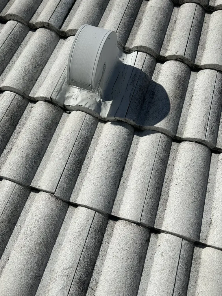 Metal roof vent with sealed flashing base on gray concrete barrel tile roof