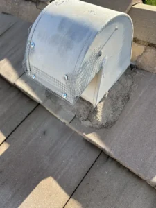 Rooftop vent cap covered with wire mesh screening and cement patching to block rodent entry